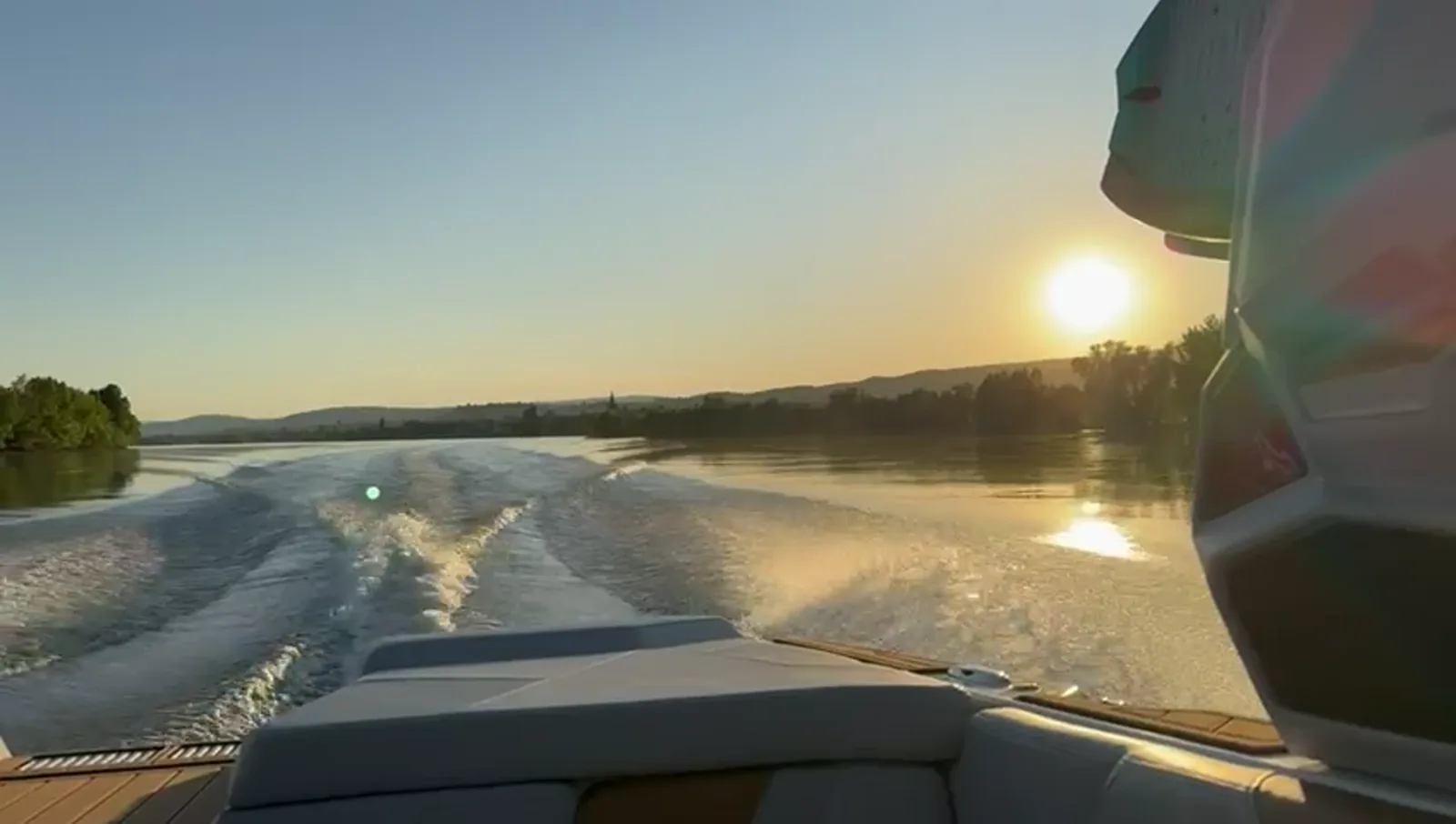 Boot-Heck, Wake und Rheinlandschaft im Sonnenuntergang